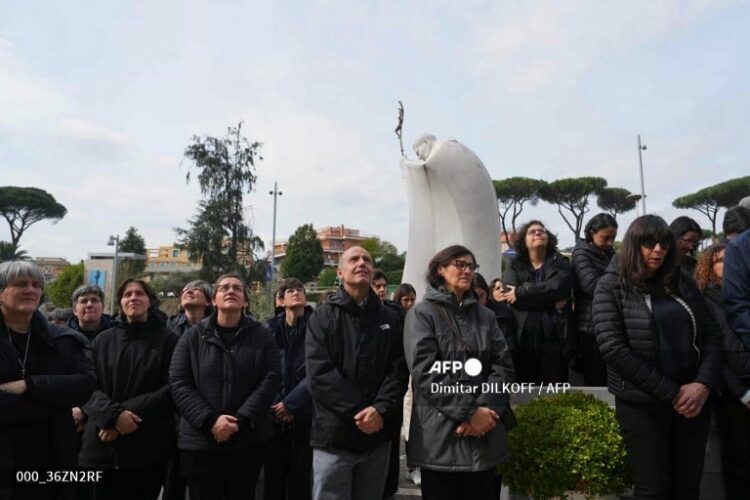 Varias personas oran por el Papa