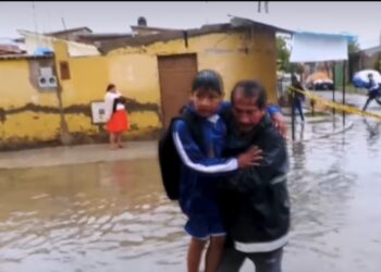 Un estudiante es llevado en brazos por la inundación en un colegio de Cochabamba.