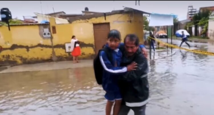 Un estudiante es llevado en brazos por la inundación en un colegio de Cochabamba.