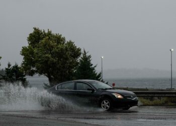 Un auto escapa de las olas agresivas por el huracán. Foto: AFP