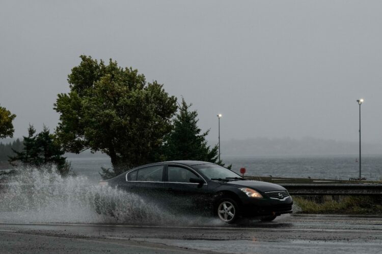 Un auto escapa de las olas agresivas por el huracán. Foto: AFP
