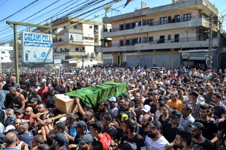 Una muntitudinaria concentración lleva uno de los cuerpos recuperados del naufragio. Foto: AFP