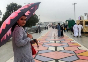 Una mujer pasea bajo un paraguas en Al Namas en Arabia Saudita. Foto: AFP.