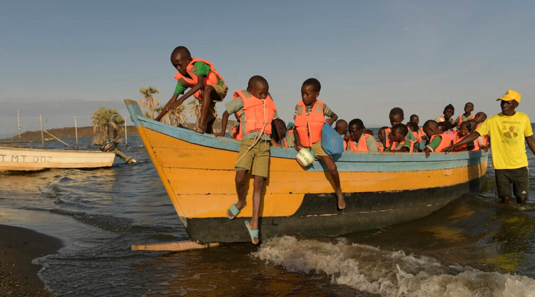 Niños de Bahía El Molo bajan de una lancha para ir a la escuela en el norte de Kenia. Foto: AFP.