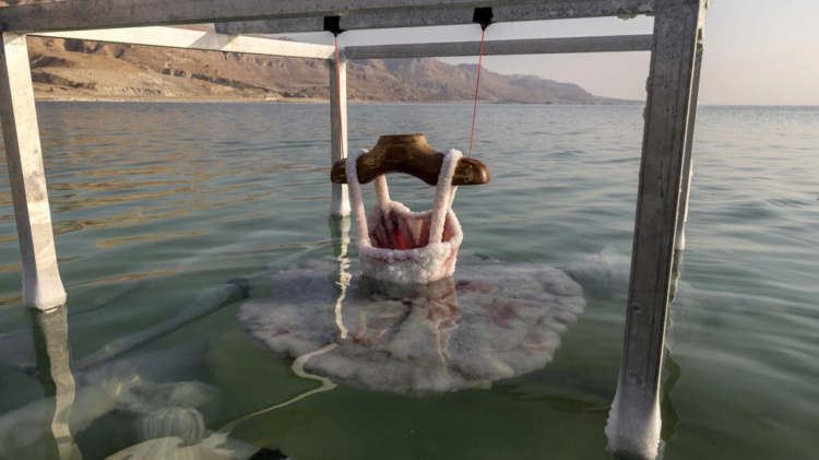 Un vestido de bailarina es sumergido en el mar Muerto por la artista israelí Sigalit Landau. Foto: AFP.