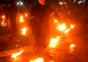 Jóvenes enmascarados participan en la batalla de las bolas de fuego, en Nejapa, unos 20 km al norte de la capital de El Salvador. Foto: AFP.