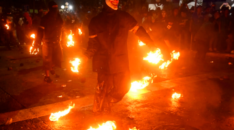 Jóvenes enmascarados participan en la batalla de las bolas de fuego, en Nejapa, unos 20 km al norte de la capital de El Salvador. Foto: AFP.