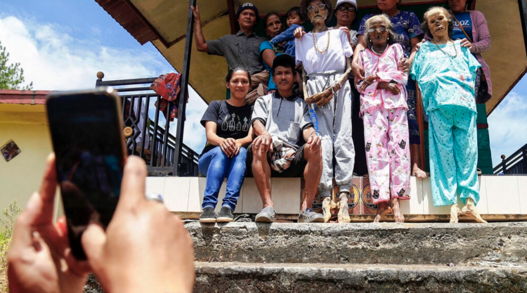 Una familia indonesia se toma una fotografía con los cadáveres de sus antepasados durante el rito tradicional del Manene en Lembang. Foto: AFP.