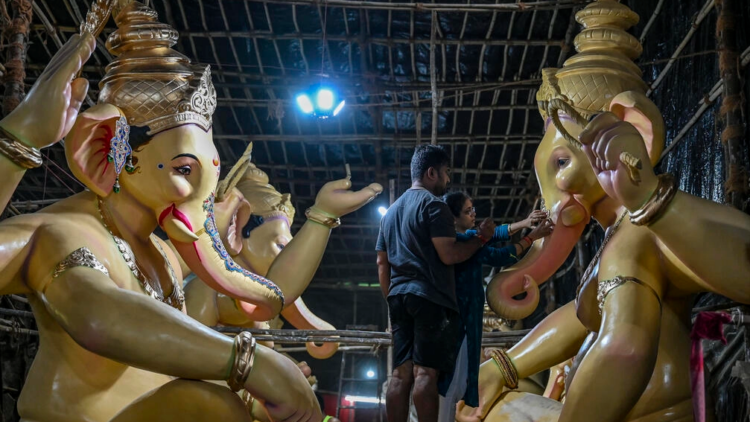 Unos artistas trabajan en una estatua de Ganesh, el dios hindú con cabeza de elefante, en un taller en Bombay. Foto: AFP.