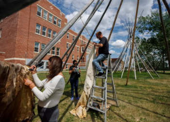 Estudiantes fijan una piel de alce a un tipi fuera de la universidad Nuhelt'ine Tahiyots'i Nistameyimakanak Blue Quills, en St. Paul, Alberta, Canadá. Foto: AFP.