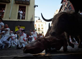 Corredores y toros toman una curva durante el primer encierro de las fiestas de San Fermín. Foto: AFP.