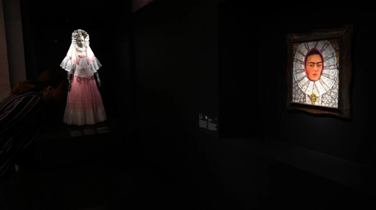 Un autorretrato de la pintora mexicana Frida Kahlo, ataviada con un resplandor, tocado de origen religioso, frente a un traje indígena. Foto: AFP.