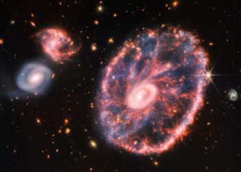 Detrás de la Rueda de Carro brillan otras dos galaxias más pequeñas; además se puede ver otras estructuras. Foto: AFP.
