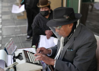 El mecanógrafo Rogelio Condori redacta en su vieja máquina de escribir un documento para una indígena aymara en una calle céntrica de La Paz. Foto: AFP.