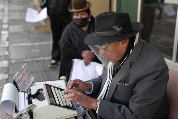 El mecanógrafo Rogelio Condori redacta en su vieja máquina de escribir un documento para una indígena aymara en una calle céntrica de La Paz. Foto: AFP.