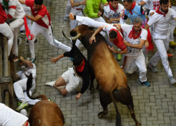 Un participante es embestido por un toro en el quinto encierro de la fiesta de San Fermín, en Pamplona. Foto: AFP.