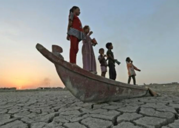 Niños se suben a un bote sobre el lecho seco del pantanal de Chibayish, en el sur de Irak. Foto: AFP.