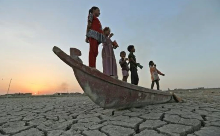 Niños se suben a un bote sobre el lecho seco del pantanal de Chibayish, en el sur de Irak. Foto: AFP.
