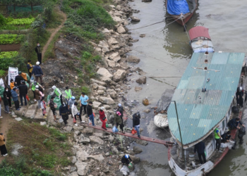 Residentes caminan hacia un bote en el Río Rojo para conmemorar el Día del Dios de la Cocina, antes del Año Nuevo Lunar, en Hanoi, Vietnam. Foto: AFP.