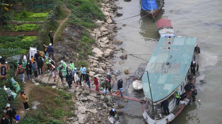Residentes caminan hacia un bote en el Río Rojo para conmemorar el Día del Dios de la Cocina, antes del Año Nuevo Lunar, en Hanoi, Vietnam. Foto: AFP.