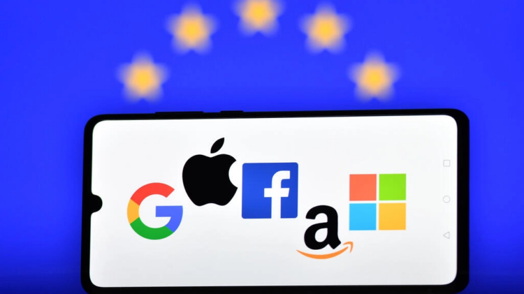 Los logotipos de los gigantes tecnológicos Google, Apple, Facebook, Amazon y Microsoft, fotografiados en la pantalla de un telófono móvil delante de una bandera de la Unión Europea. Foto: AFP.