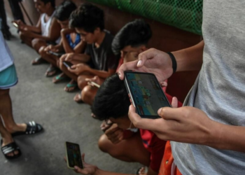 Jóvenes filipinos utilizan sus teléfonos móviles para jugar a 'Axie Infinity' en un callejón de Malabon, suburbio de Manila. Foto: AFP.