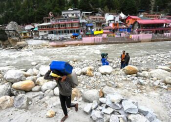 Unos trabajadores cargan con bidones llenos de agua derretida del glaciar Gangotri, fuente primaria para el río sagrado Ganges, el 15 de septiembre de 2022 en Uttarakhand, India. Foto: AFP.