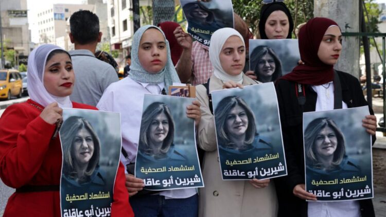 Palestinas sostienen carteles en los que aparece la veterana periodista de 'Al-Jazeera' Shireen Abu Akleh, en la ciudad cisjordana de Hebró. Foto: AFP.