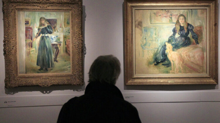 Una persona contempla los cuadros 'Julie tocando el violín' (izq.) y 'Julie Manet y su lebrel Laërte', expuestos en una retrospectiva dedicada a la pintora impresionista Berthe Morisot, en el Museo Marmottan-Monet de París. Foto: AFP.