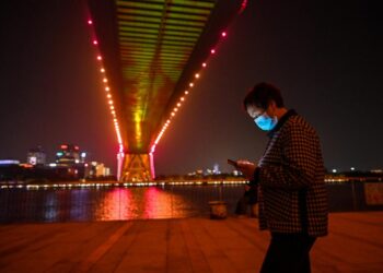 Una mujer mira su teléfono móvil el 9 de noviembre de 2022 bajo el puente Lupu de Shanghái. Foto: AFP.