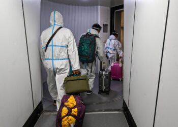 Pasajeros con trajes de protección desembarcan en el aeropuerto de Shanghái tras llegar en avión desde París, el 18 de enero de 2022. Foto: AFP.