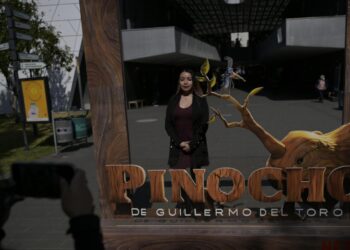 Una mujer posa para una foto junto a un anuncio de la película "Pinocho", del director mexicano Guillermo del Toro, en la Cineteca Nacional de la Ciudad de México, el 16 de diciembre de 2022. Foto: AFP.