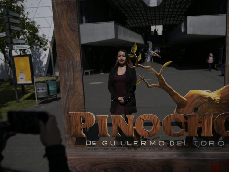 Una mujer posa para una foto junto a un anuncio de la película "Pinocho", del director mexicano Guillermo del Toro, en la Cineteca Nacional de la Ciudad de México, el 16 de diciembre de 2022. Foto: AFP.