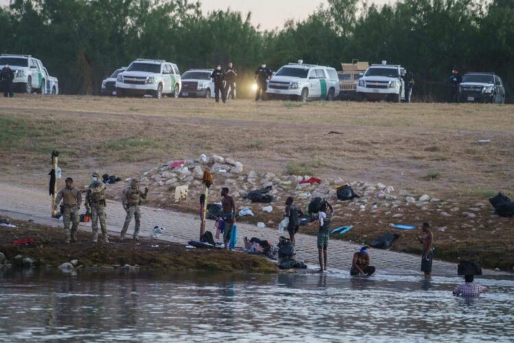 Migrantes haitianos cruzan el Río Grande hacia Estados Unidos bajo la vigilancia de la policía fronteriza estadounidense en Ciudad Acuna (México) el 23 de septiembre de 2021. Foto: AFP.