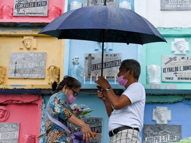 Una pareja de filipinos enciende velas por el Día de Todos los Santos en el Cementerio Manila Norte de la capital de Filipinas, el 1 de noviembre de 2022. Foto: AFP.