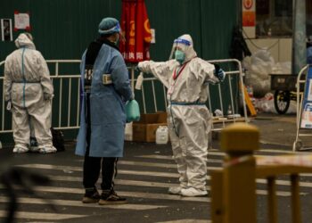 Personal de seguridad con trajes especiales custodia el acceso a una zona residencial de Pekín confinada por las restricciones de COVID-19. Foto: AFP.