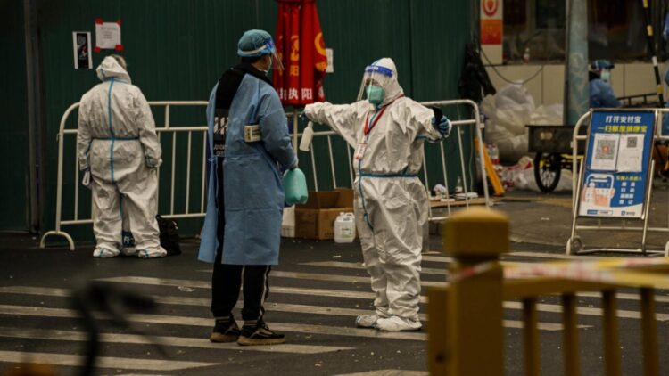 Personal de seguridad con trajes especiales custodia el acceso a una zona residencial de Pekín confinada por las restricciones de COVID-19. Foto: AFP.