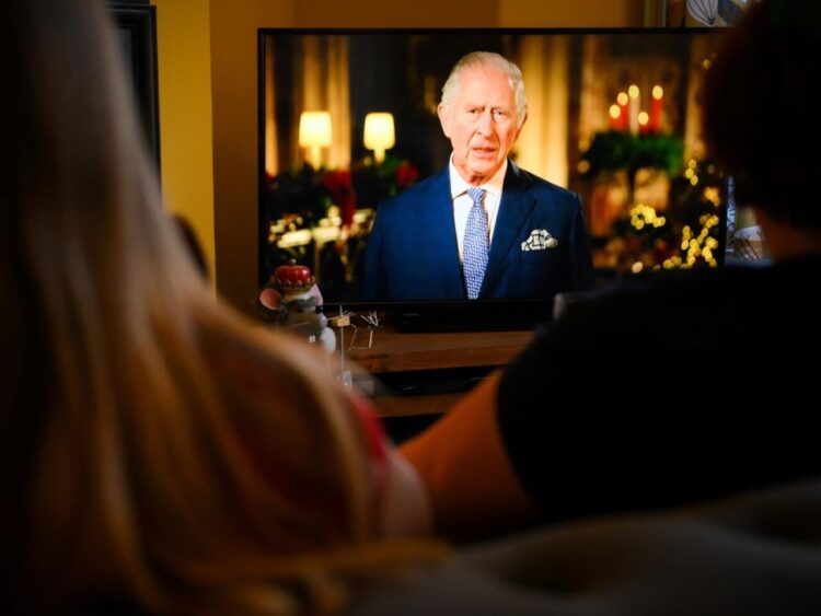 Una familia mira el discurso navideño del rey Carlos III, en Liverpool, Reino Unido, el 25 de diciembre de 2022. Foto: AFP.