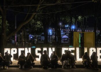 Personas sentadas frente a un cartel del Open San Felipe en Bogotá, el 3 de diciembre de 2022. Foto: AFP.