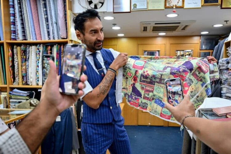 El sastre Roshan Melwani habla con un cliente mientras su equipo lo graba en el negocio Sam's Tailor de Hong Kong, el 25 de octubre de 2022. Foto: AFP.