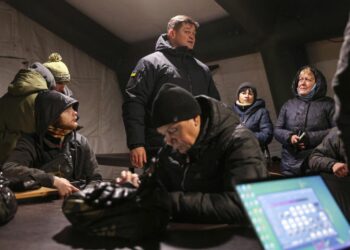 El responsable de la administración regional militar de Jersón, Yaroslav Yanushevich (c), habla con unos habitantes de Jersón en un Punto de Invencibilidad, donde pueden calentarse, cargar sus dispositivos y usar internet, el 5 de diciembre de 2022. Foto: AFP.
