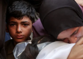 Un niño observa asu madre llorando por la muerte de su hermano menor/AFP