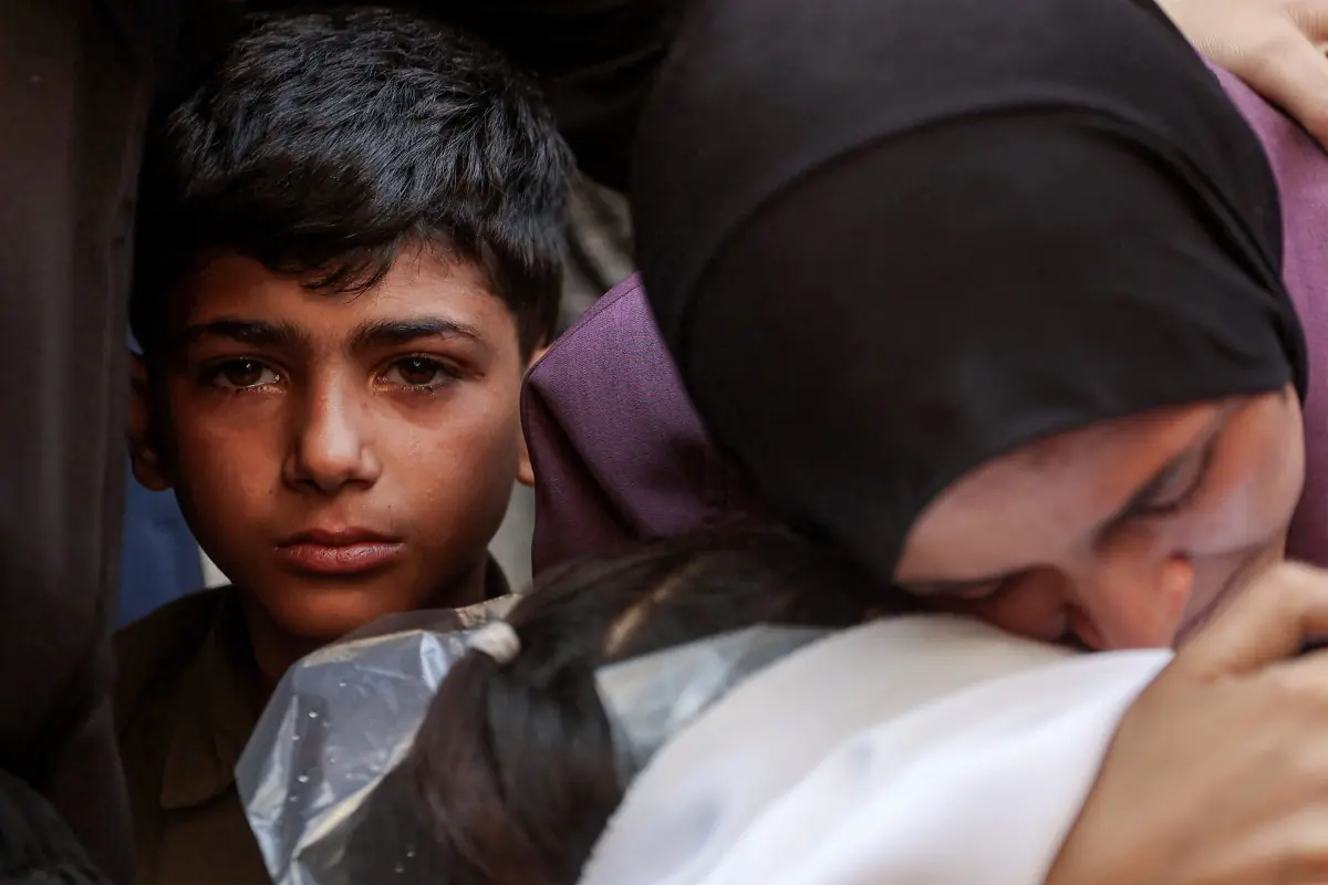 Un niño observa asu madre llorando por la muerte de su hermano menor/AFP