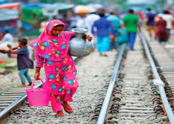 Una mujer carga agua potable para su consumo en Dhaka, Bangladesh.