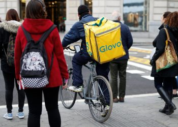 Un repartidor de Glovo aguarda a cruzar una calle con su bicicleta, el 3 de diciembre de 2019 en Barcelona. Foto: AFP.