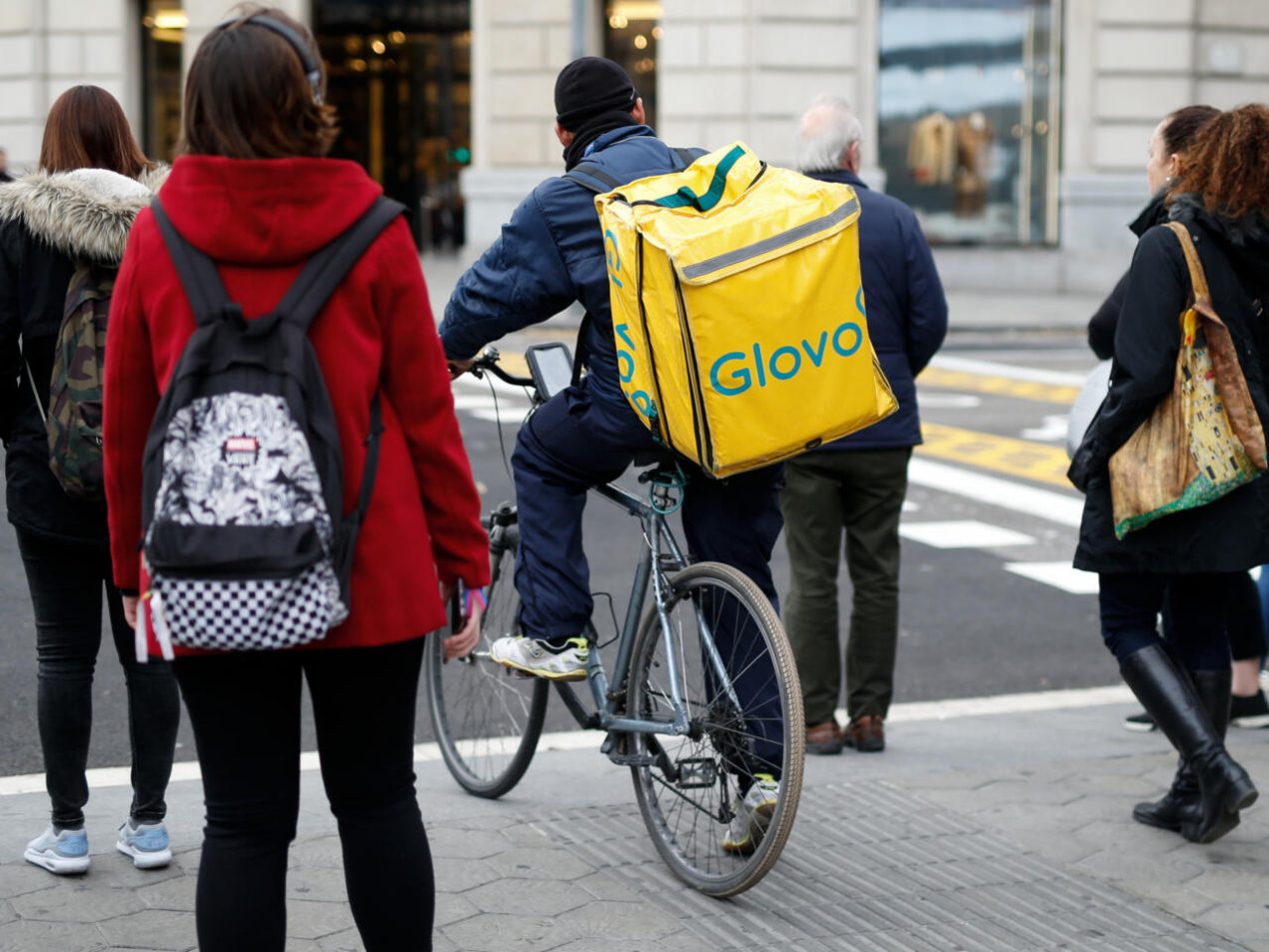 Un repartidor de Glovo aguarda a cruzar una calle con su bicicleta, el 3 de diciembre de 2019 en Barcelona. Foto: AFP.