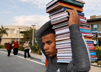 Un hombre lleva una pila de libros a la 54º Feria Internacional del Libro de El Cairo, en Egipto, el 29 de enero de 2023. Foto: AFP.