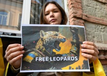 Activista junto a una imagen en apoyo a #FreeTheLeopards. Foto: AFP.