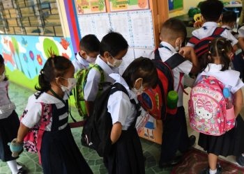 Un grupo de escolares con mascarillas entra en un aula el primer día del curso en Filipinas, el 22 de agosto de 2022 en Quezon City, un suburbio de Manila. Foto: AFP.