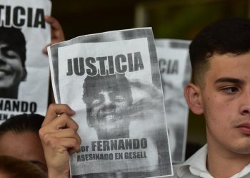 Un hombre sostiene un cartel con el retrato de Fernando Báez Sosa, asesinado a golpes hace tres años en Villa Gesell, Argentina, durante una protesta de estudiantes en Asunción en apoyo a la familia de Báez, de origen paraguayo, el 18 de enero de 2023. Foto: AFP.
